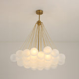 The Orb 37 Light Cluster Suspension - Gold features modern frosted glass globes clustered together, suspended by gold rods from a brass mount, adding striking elegance and brightness to a plain white ceiling.