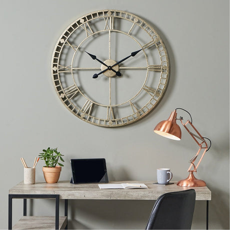 Antique Gold Iron Round Large Wall Clock, 80cm, with skeleton spoke design and Roman numerals, mounted above a desk with a copper lamp in a home office setting.