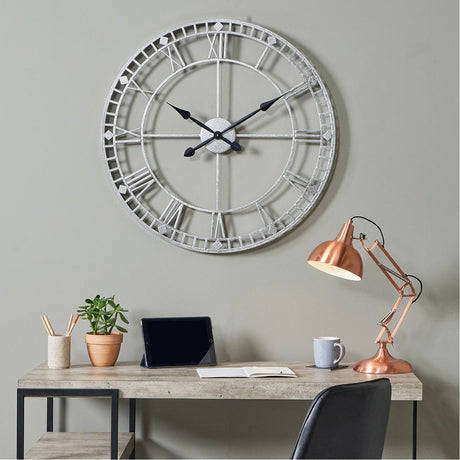 Antique Silver Iron Round Large Wall Clock, 80cm, with skeleton frame and Roman numerals, shown above a desk with a copper lamp in a home office setting.