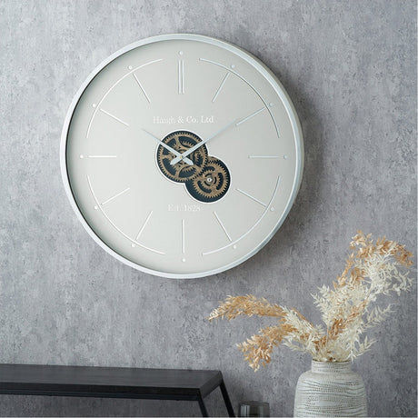Ivory & Silver Working Cog Wall Clock, 60cm round wall clock with silver frame, ivory dial, exposed gear mechanism, and stick markers, shown mounted in a living room setting.