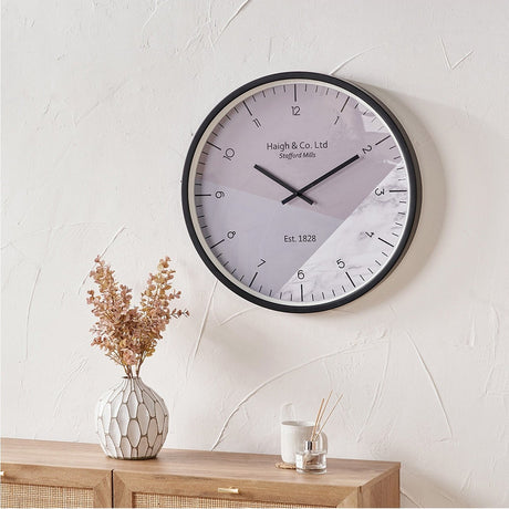 Black Metal Printed Face Wall Clock, 60cm, with grey and marble-effect dial and bold numerals, shown on a plain wall above a wooden sideboard in a living room.