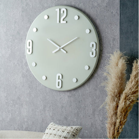 Round grey 80cm wall clock with oversized silver numerals and dot markers, silver hands, mounted on a grey textured wall above a sofa.