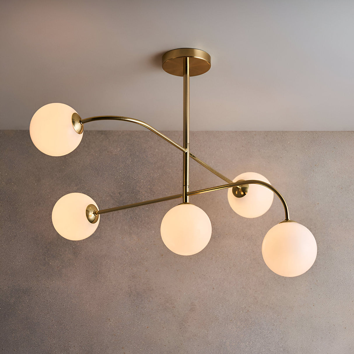 Endon Sinclair 5 light semi-flush ceiling light in brushed brass with white opal glass globes on curved arms, shown against a light grey background.