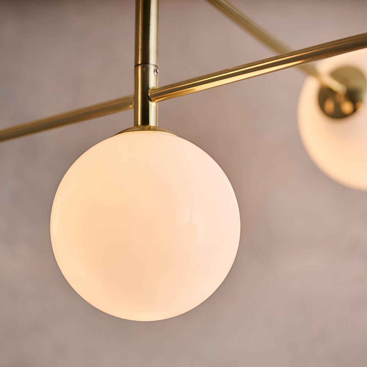 Close-up of Endon Sinclair semi-flush ceiling light globe, opal glass sphere on brushed brass arm with further globe visible alongside.