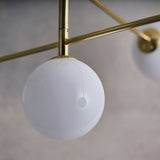 Close-up of Endon Sinclair 5 Light Semi-Flush Ceiling Light in brushed brass, showing a white glass globe suspended from a slim brass arm.