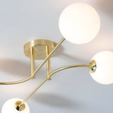 Endon Sinclair 4 light semi-flush ceiling light in brushed brass, viewed from below showing the central plate, curved arms and white glass globe shades.