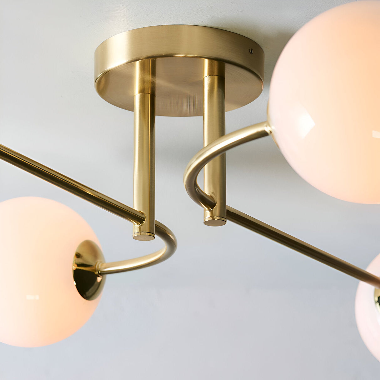 Close-up of Endon Sinclair 4 Light Semi-Flush Ceiling Light in brushed brass, showing the central plate, curved arms and opal glass globe shades.