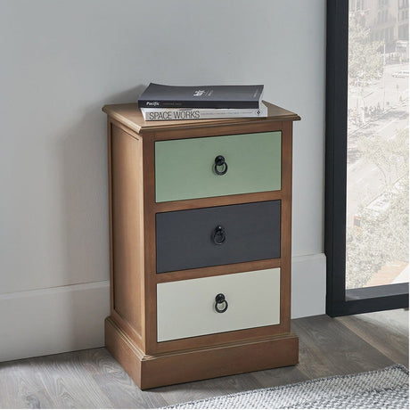 Loft Sage Multicoloured Pine 3 Drawer Unit with sage green, dark grey and cream drawers and round metal handles, shown in a bedroom beside a window.