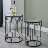 Caprisse set of 2 round side tables with mirrored glass tops and graphite iron curved-link frames, styled in a living room with wine glass and bottle.