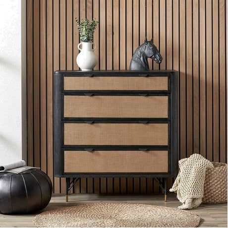 Fiji Black Acacia & Rattan 4 Drawer Unit with woven rattan fronts and black metal legs, styled with a white vase and horse head sculpture against wood-panelled wall.