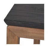 Close-up of the Gio Black & Acacia Dining Table showing a black wood-grain tabletop edge meeting a natural acacia wood leg joint, on a plain white background.