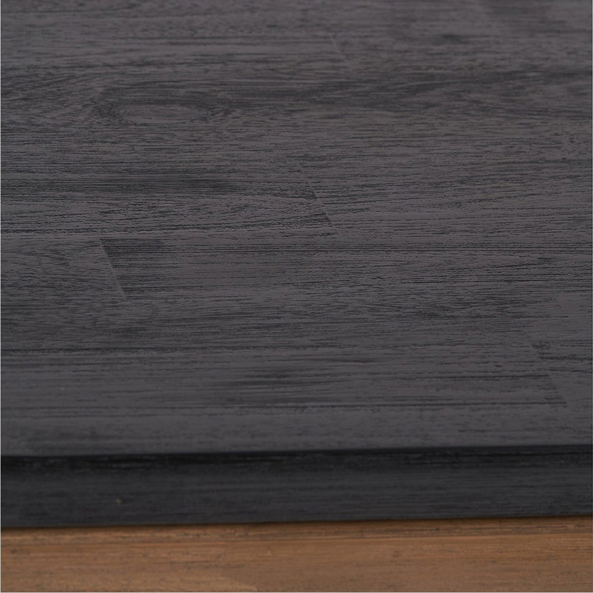 Close-up of the Gio Black & Acacia Dining Table showing the black wood-grain tabletop edge with visible brush texture above a natural acacia base.