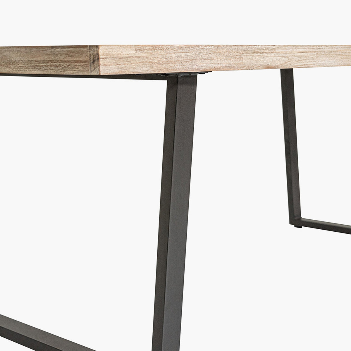 Close-up of the Marca dining table's sand wash acacia tabletop edge and angled black metal cross-brace legs, shown against a plain white background.