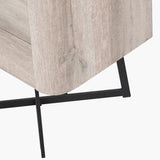 Close-up of the Ukiah tall chest of drawers' base, showing a grey oak veneer corner edge on angled black metal cross-brace legs, on a white background.