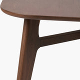 Close-up of the Elias Dark Ash Wood Retro Dining Table showing a rounded tabletop edge, angled tapered leg, and cross-brace joinery in dark ash wood on a plain white background.