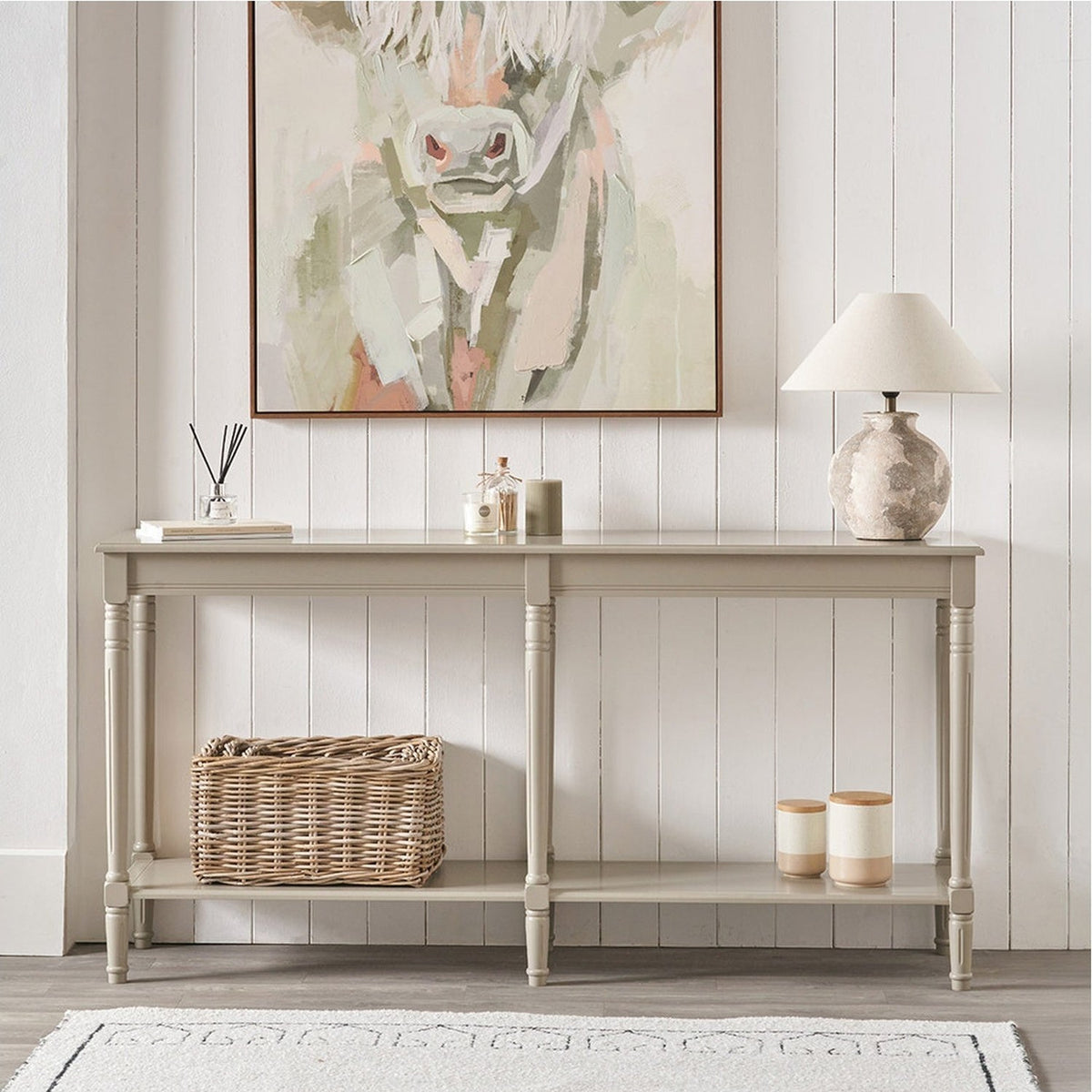 Heritage Putty Pine Large Console Table with turned legs and lower shelf, styled in a hallway with wall art, lamp, basket and decor accessories.