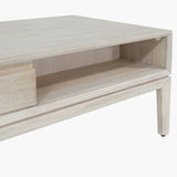 Close-up of the Gio White Sand Acacia 2 Drawer Coffee Table showing the open shelf, wood-grain finish, and tapered leg with foot cap on a white background.