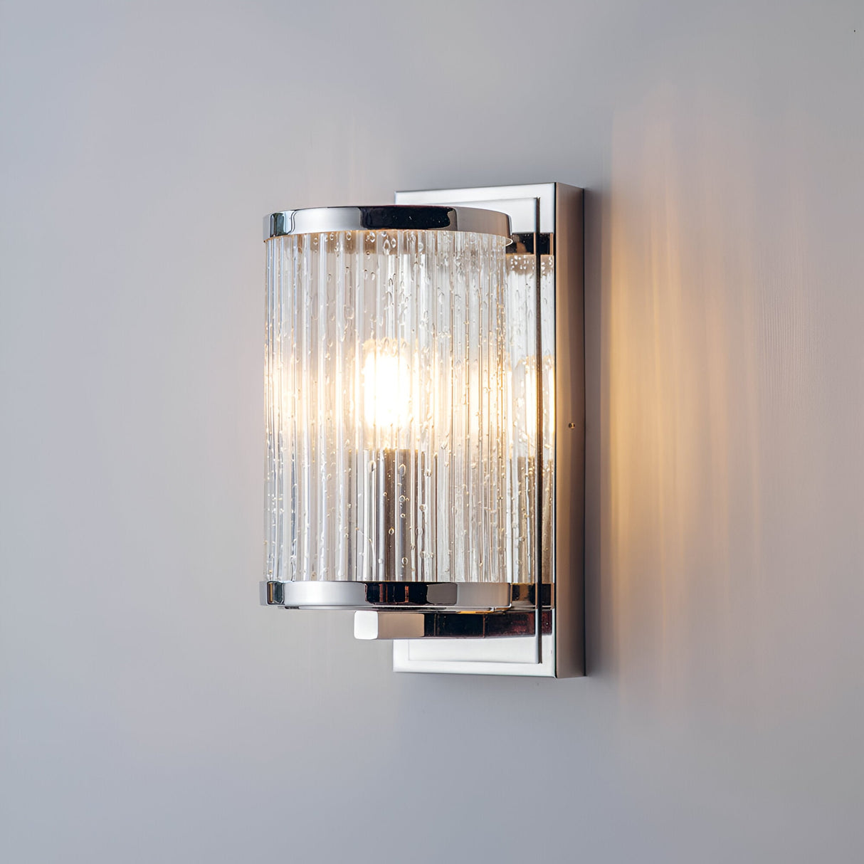 Endon Winslow wall light with clear ribbed bubbled glass shade and nickel-plated metal frame, lit by a single E14 bulb, mounted on a pale wall.