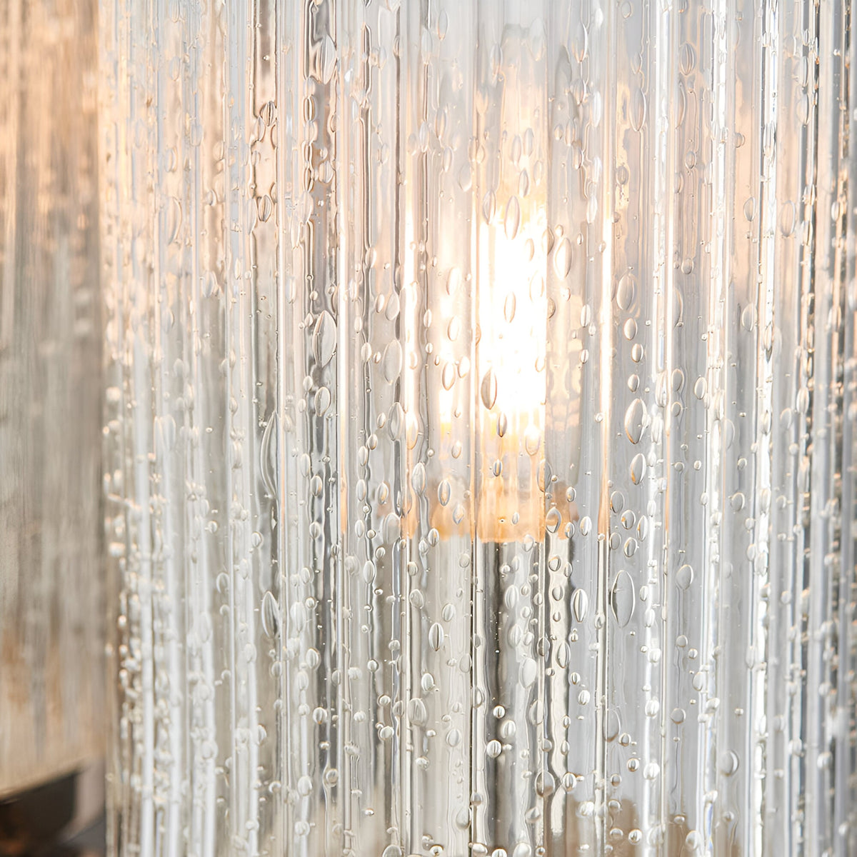 Close-up of Endon Winslow wall light showing clear ribbed glass shade with bubble detailing, illuminated by a warm filament bulb.