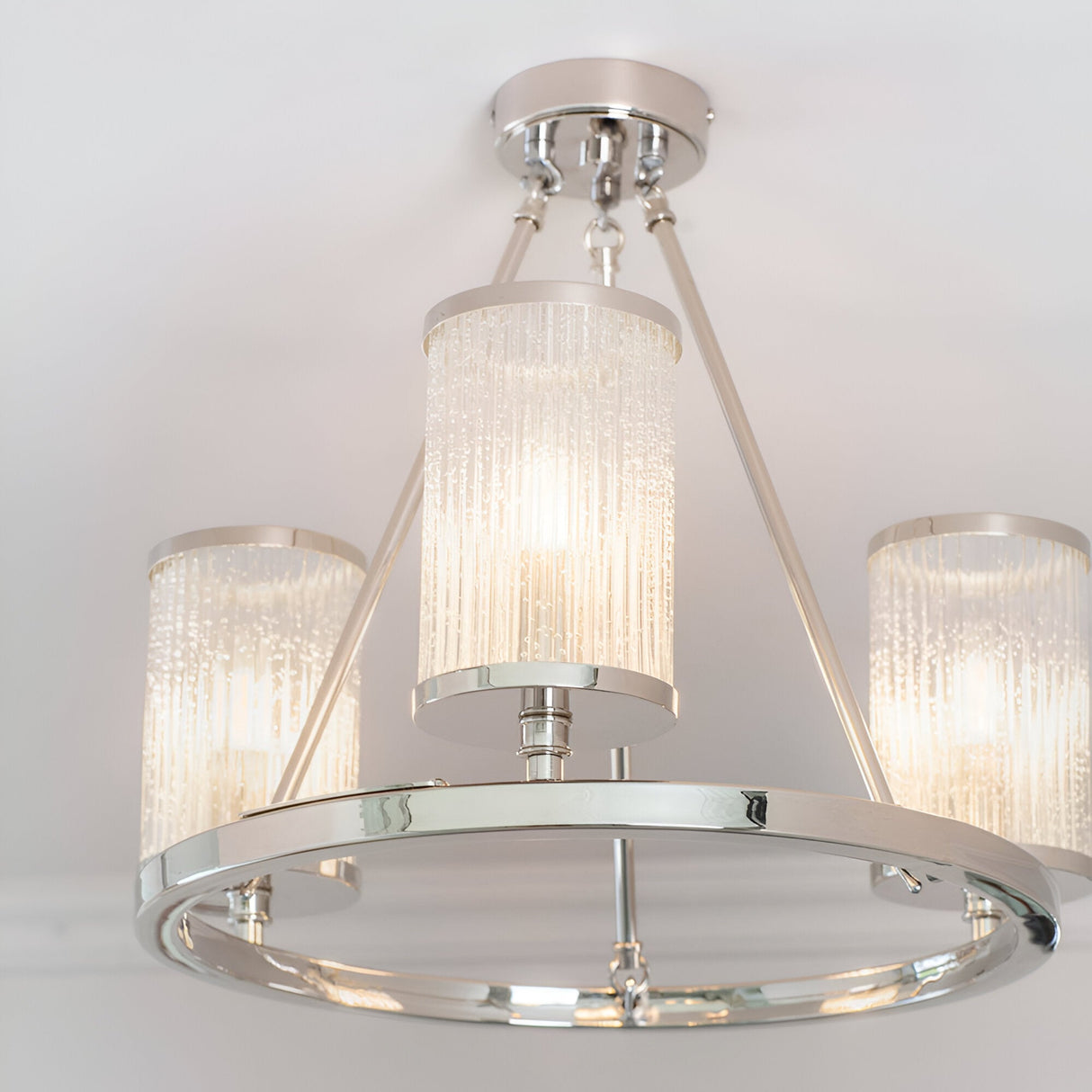 Endon Winslow 3 light semi-flush ceiling light in nickel with textured glass cylinder shades on a circular ring frame, shown illuminated.