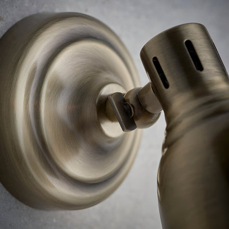 Close-up of Endon Daneford single spotlight in antique brass, showing the adjustable head joint and round wall plate against a light background.