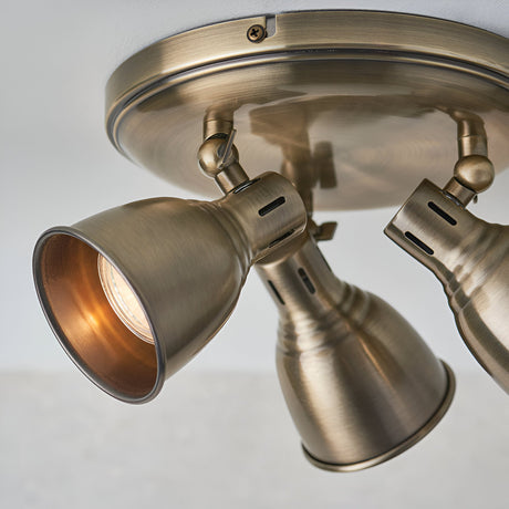 Close-up of the Endon Daneford 3 light round spotlight in antique brass, showing adjustable steel heads on a circular ceiling plate.