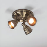 Endon Daneford 3 light round spotlight in antique brass, three adjustable heads on a circular ceiling plate, mounted on a white ceiling.