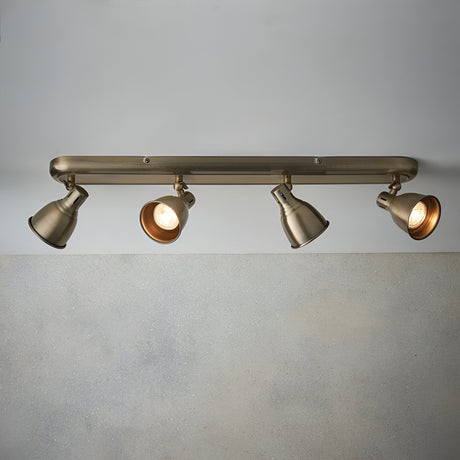 Endon Daneford 4 Light Spotlight in antique brass, ceiling-mounted bar with four adjustable steel heads angled outward, shown against a pale wall.