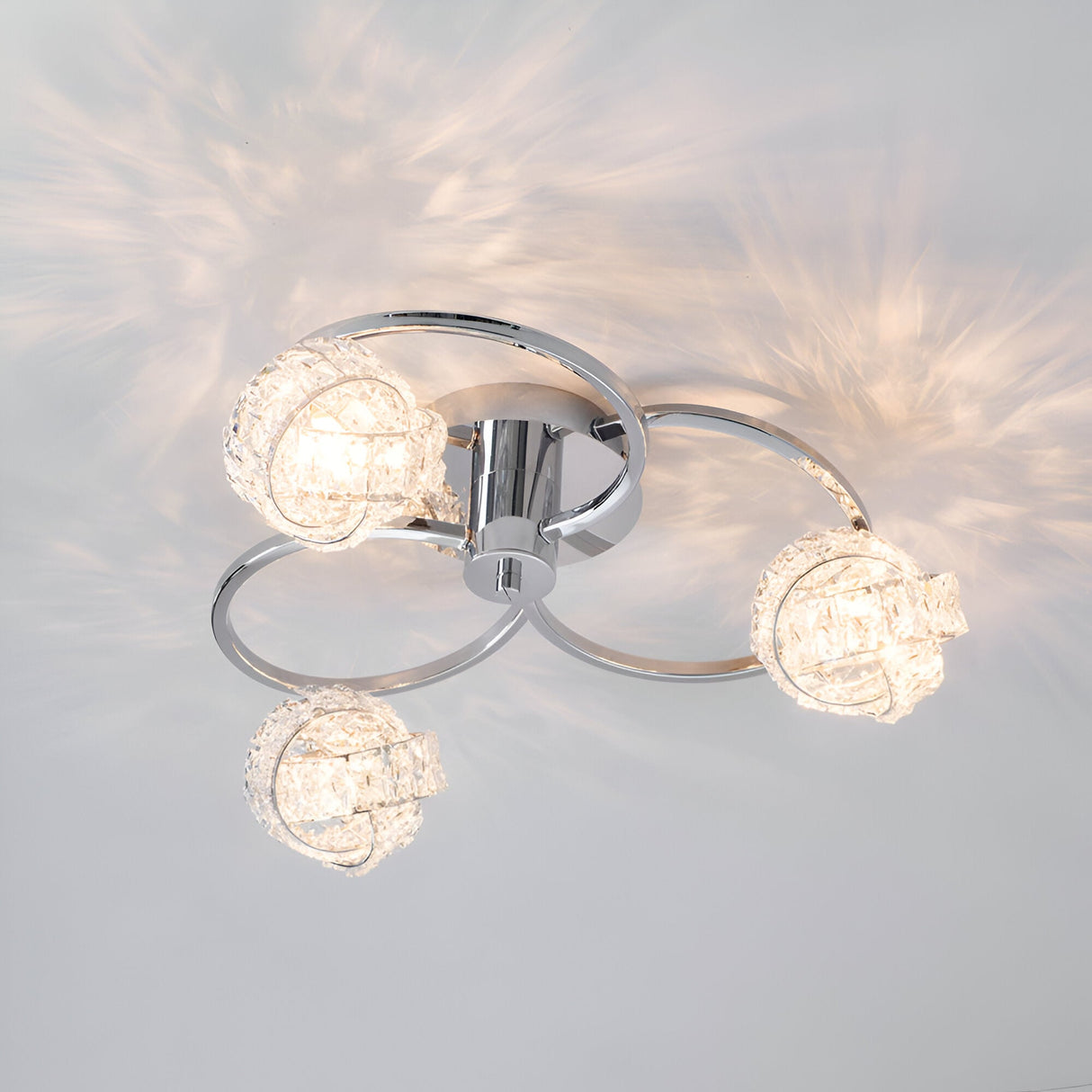 Endon Seraphine 3 light semi-flush ceiling light in polished chrome with faceted crystal globe shades, casting patterned light across the ceiling.
