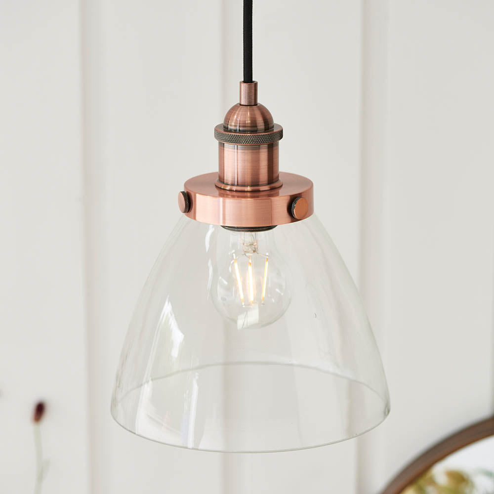 Endon Wentworth industrial pendant light in copper with clear glass bell shade, knurled lamp holder, exposed E27 filament bulb and black fabric flex.