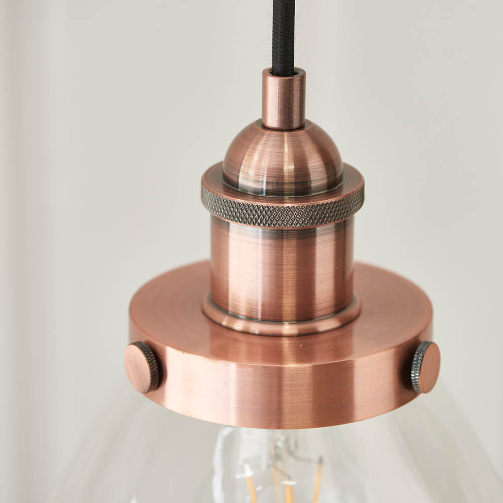 Close-up of Endon Wentworth copper pendant light with knurled lamp holder, plated metalwork, black fabric flex and clear glass shade with filament bulb.