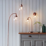 Endon Wentworth pendant lights in copper with clear glass shades, shown with a matching floor lamp, table lamp and wall light against panelled walls.