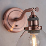 Close-up of the Endon Wentworth copper wall light showing the knurled lamp holder, adjustable knuckle, toggle switch and clear glass shade with filament bulb.