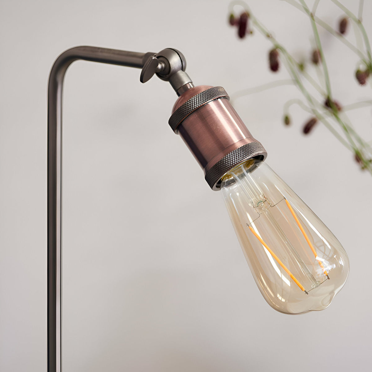 Brackley Table Lamp in copper and silver, close-up of adjustable knuckle joint and knurled E27 bulb holder with exposed filament bulb, plain light background.