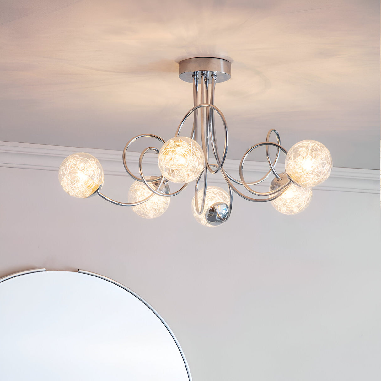 Endon Sabine six-light semi-flush ceiling light in chrome with swirling steel arms and glass globe shades, mounted in a room above a round mirror.