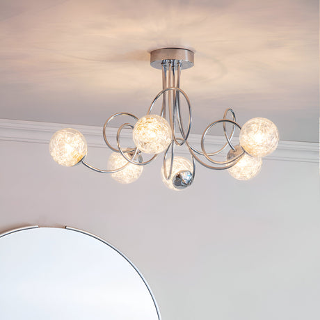 Endon Sabine six-light semi-flush ceiling light in chrome with swirling steel arms and glass globe shades, mounted in a room above a round mirror.