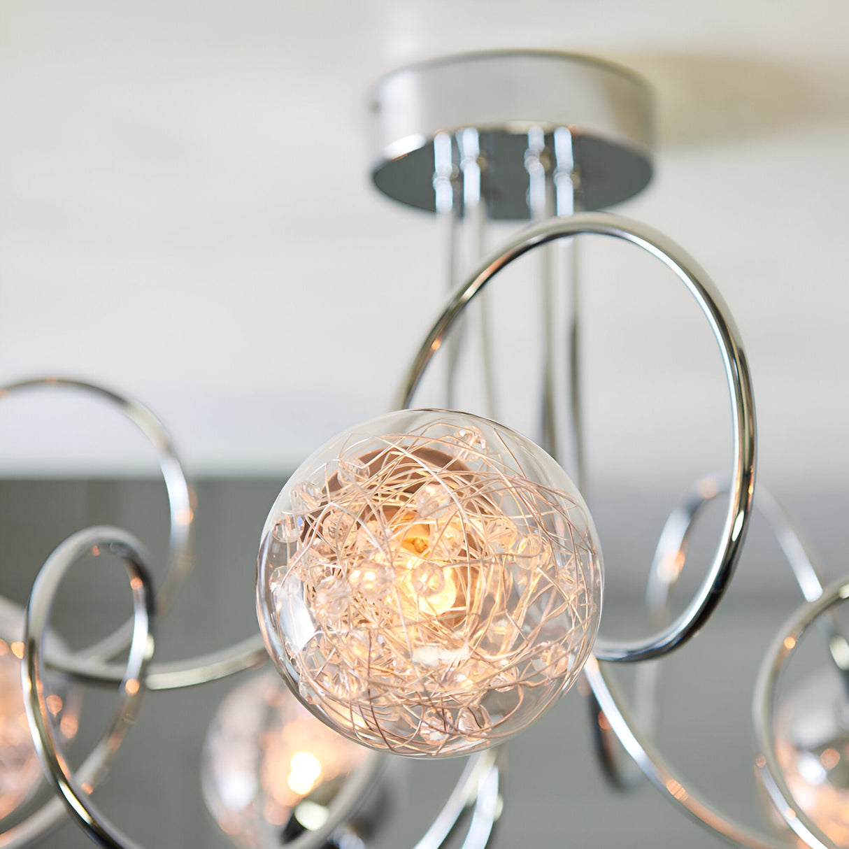 Close-up of the Endon Sabine semi-flush ceiling light in chrome, showing a glass globe shade with internal wire detail and curved chrome arms.