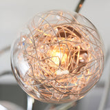 Close-up of the Endon Sabine semi-flush ceiling light showing a lit G9 lamp inside a clear glass globe wrapped with chrome wire and crystal beads.