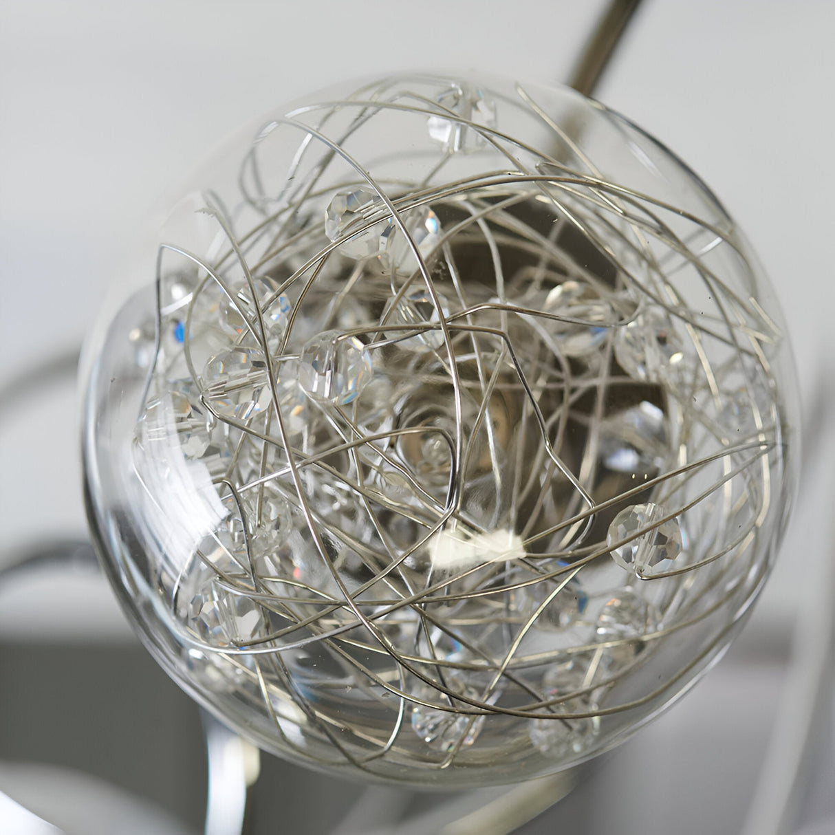 Close-up of one glass globe from the Endon Sabine semi-flush ceiling light, showing chrome wire coils and crystal beads around a G9 lamp.