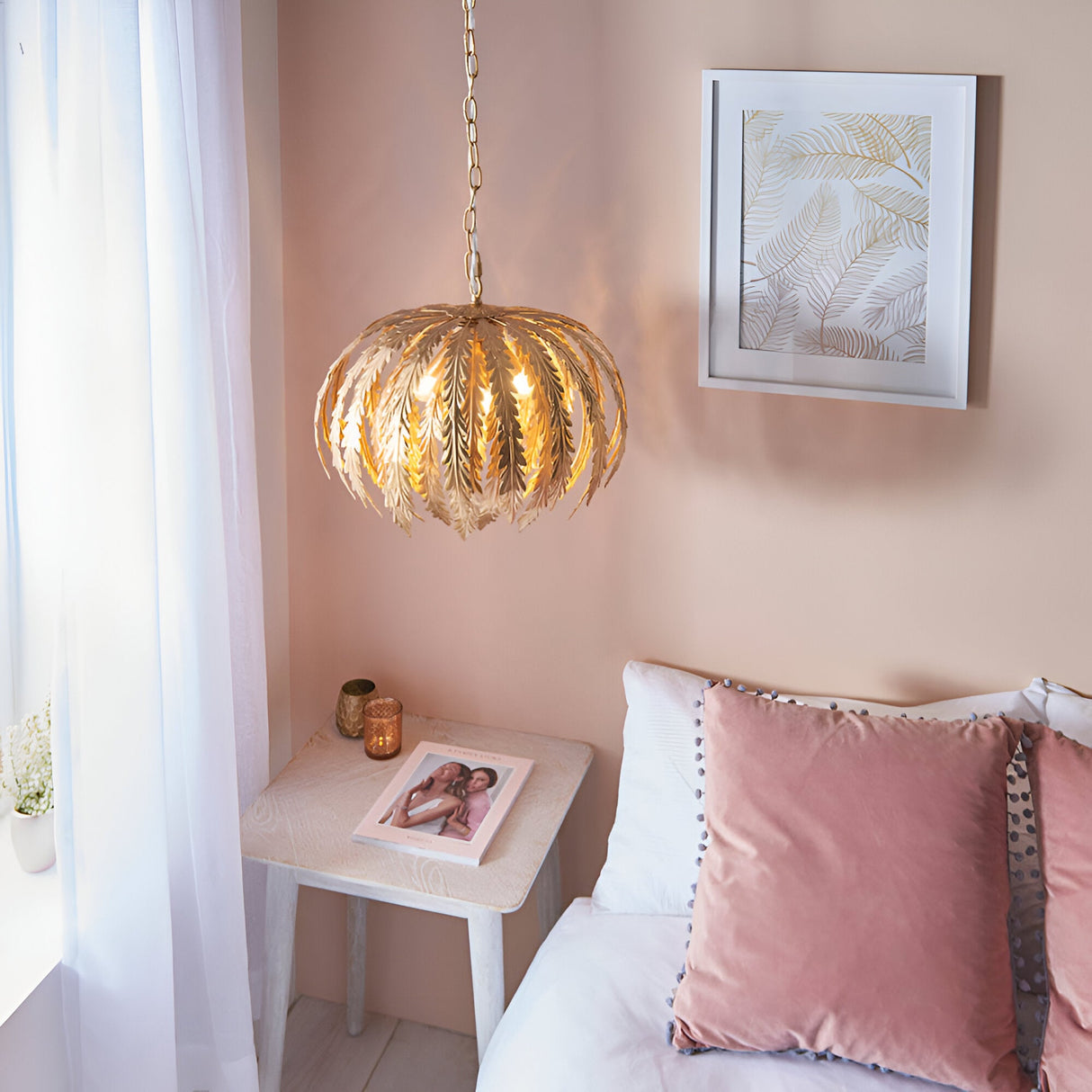 Endon Colette 3 light pendant in gold leaf with layered floral leaf shades, hanging on a chain above a bedside table in a soft pink bedroom.