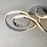 Endon Neve semi-flush ceiling light in polished chrome, shown close-up with interlocking looped LED bands mounted to a light ceiling.