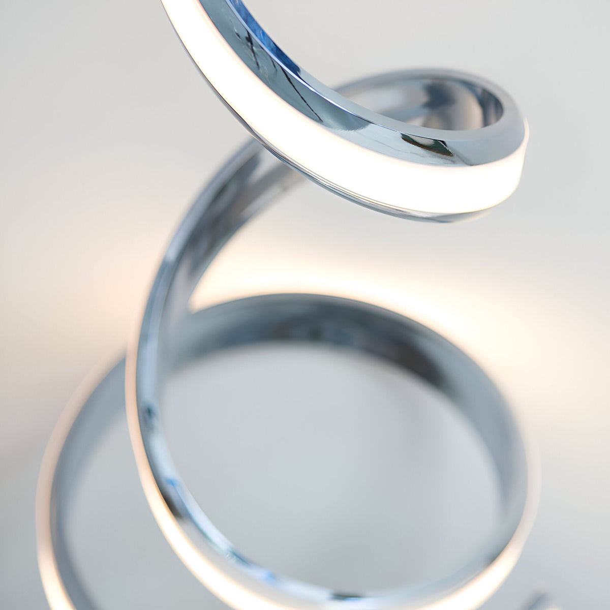 Close-up of the Endon Neve table lamp showing its polished chrome curves and white LED diffuser forming a sculptural spiral form.