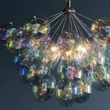 Endon Brenworth 6 light pendant in chrome with a cluster of iridescent glass globe shades reflecting shifting colours against a dark background.