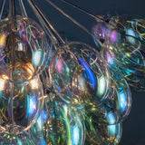 Close-up of Endon Brenworth 6 light pendant showing clustered iridescent glass shades with chrome fittings casting shifting blue, purple and amber tones.