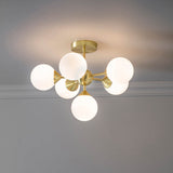 Fitzroy 6 Light Semi-Flush Ceiling Light in gold, featuring brass arms with six round opal glass globes, mounted on a grey ceiling.