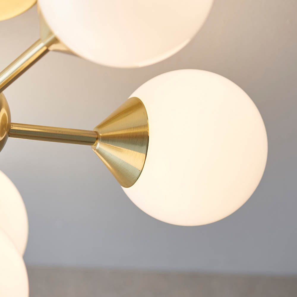 Fitzroy 6 Light Semi-Flush Ceiling Light in Gold, close-up of brass conical fitting and opal glass globe shade against a grey wall.