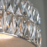 Close-up of the Marguerite LED round pendant in chrome, showing faceted crystal panels and a fabric diffuser with warm light glowing through.