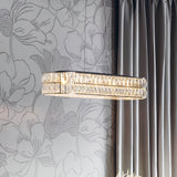 Endon Marguerite linear pendant in polished chrome with faceted crystals, suspended by a floral-patterned wall beside grey curtains in a modern interior.