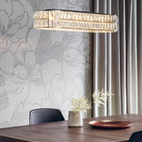 Endon Marguerite linear pendant in polished chrome with faceted crystals, illuminated above a wooden dining table against a floral wallpaper backdrop.