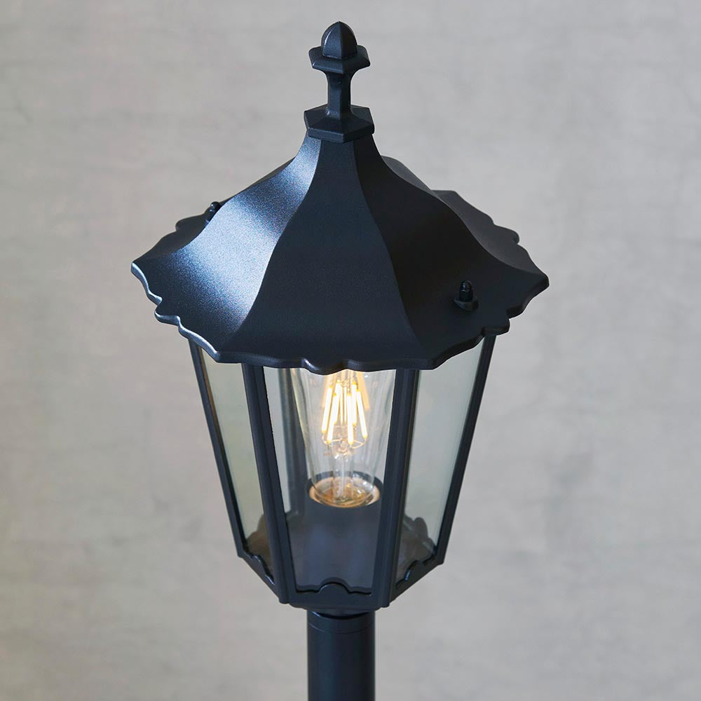 Endon Ashshaw bollard light in matt black die cast aluminium with a traditional lantern head, clear glass panels and a visible filament E27 bulb.
